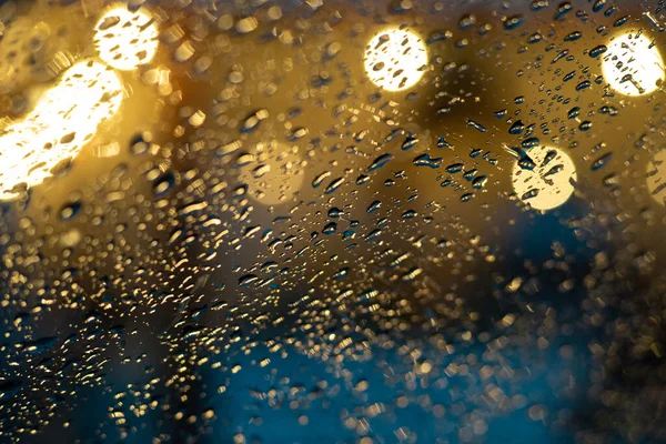 Yumuşak odaklanma. Şehir ışıklarının arka planında cam üzerine yağmur damlaları, güzel bulanık bokeh