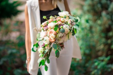 Farklı renkte güller ve okaliptüsler düğün organizatörünün ellerinde.