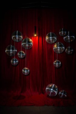 Şenlikli dekor, misafirler için bir fotoğraf alanı tasarımı - aynalı disko topları kırmızı kadife perdenin arka planında.