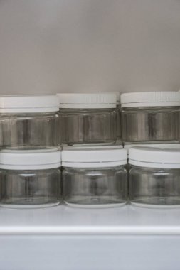 Beyaz arka planda kozmetik ürünleri depolamak için büküm kapağı olan şeffaf bir kap