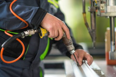 Seçici odaklanma, plastik pencere üretimi. Kendini tıklatan bir vidayı plastik bir pencerenin çerçevesine monte eden erkek bir işçinin yakın plan fotoğrafı. .