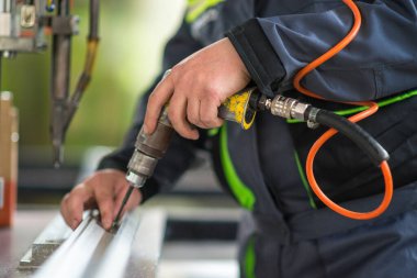 Seçici odaklanma, plastik pencere üretimi. Kendini tıklatan bir vidayı plastik bir pencerenin çerçevesine monte eden erkek bir işçinin yakın plan fotoğrafı. .