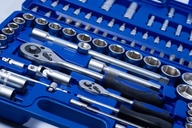 Beyaz arka planda vanadyum ve krom içeren çelik parçaları olan profesyonel cırcır ve soketler. Taşınabilir plastik bir çantada bir takım araçlar.