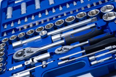 Beyaz arka planda vanadyum ve krom içeren çelik parçaları olan profesyonel cırcır ve soketler. Taşınabilir plastik bir çantada bir takım araçlar.