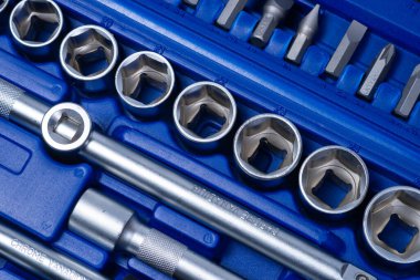 Beyaz arka planda vanadyum ve krom içeren çelik parçaları olan profesyonel cırcır ve soketler. Taşınabilir plastik bir çantada bir takım araçlar.