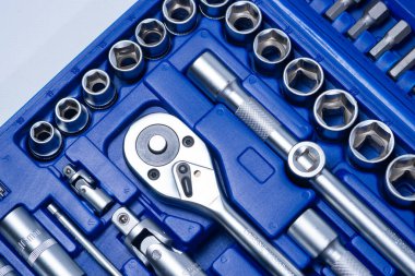 Beyaz arka planda vanadyum ve krom içeren çelik parçaları olan profesyonel cırcır ve soketler. Taşınabilir plastik bir çantada bir takım araçlar.