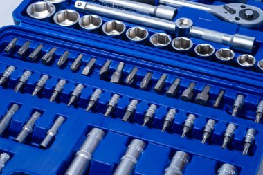 Beyaz arka planda vanadyum ve krom içeren çelik parçaları olan profesyonel cırcır ve soketler. Taşınabilir plastik bir çantada bir takım araçlar.