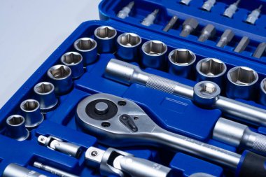 Beyaz arka planda vanadyum ve krom içeren çelik parçaları olan profesyonel cırcır ve soketler. Taşınabilir plastik bir çantada bir takım araçlar.