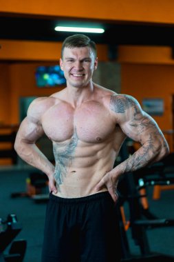 Spor salonundaki yakışıklı sporcu şişirilmiş kasları gösteriyor. spor yaşam tarzı.