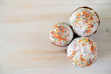 Renkli soslu Paskalya pastaları. Ahşap arka planda renkli kremalı ev yapımı Paskalya pastaları.