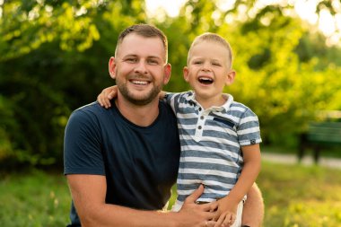 Mutlu baba bahçede oğluna mutlulukla sarılıyor. Babalar Günü. Aile mutluluğu, babalık, açık hava oyunları..