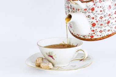 Teapot pouring tea into a cup of tea  clipart
