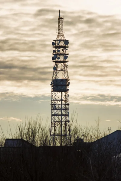 Torre de telecomunicaciones con antenas de plato y móviles al atardecer . — Foto de Stock