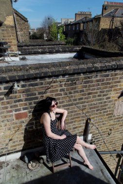 Balkonda oturan siyah polka dot elbiseli kız