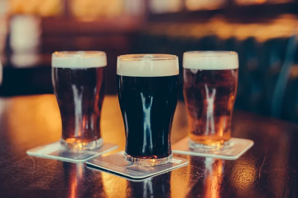 Vasos de cerveza clara y oscura sobre fondo de pub . Fotos de stock libres de derechos