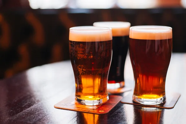 Vasos de cerveza clara y oscura sobre fondo de pub . Fotos de stock libres de derechos