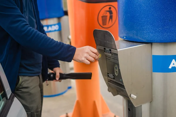 Person using self service automatic car wash vacuum machine.