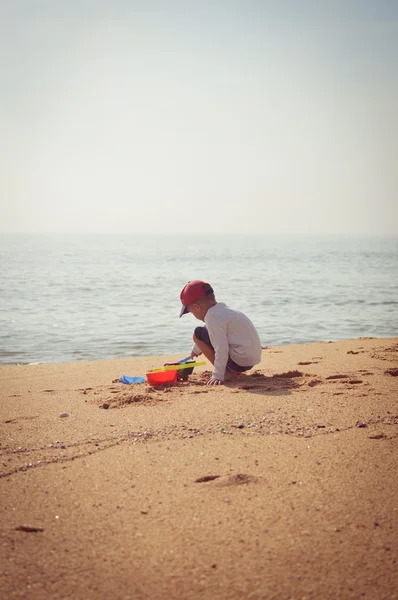 Alegre niño jugando en arena soleada playa al aire libre fondo — Foto de Stock