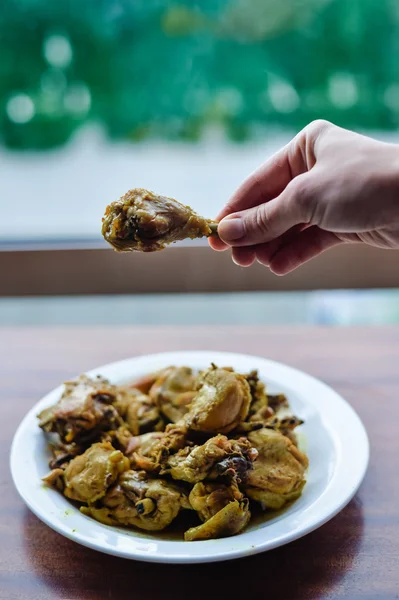 Persona que usa dedos tomando pollo del plato. Fondo mesa de madera — Foto de Stock