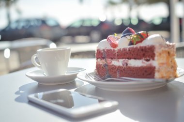 Güneşli tablo arka plan üzerinde kahve fincanı, akıllı telefon ve pastaları Üstten Görünüm.