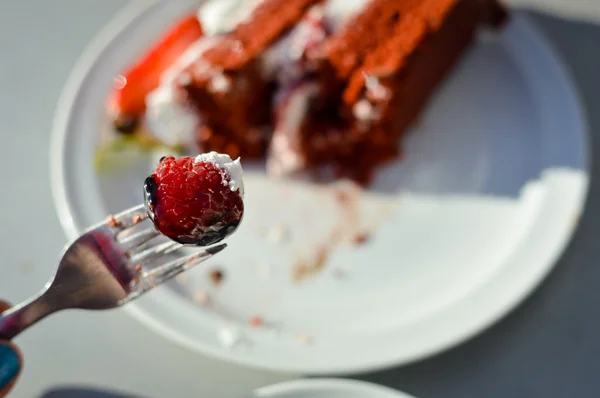 Closeup on eating chocolate cake with strawberries on a light background table — Stock Photo, Image