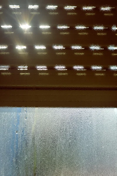 Расслабленное солнечное влажное туманное окно и стальные рольставни, задний план крупным планом — стоковое фото