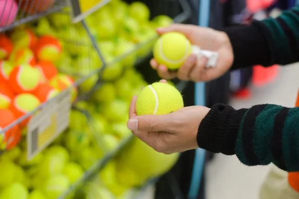 Palla scelta mano per un campo da tennis su sfondo negozio — Foto Stock