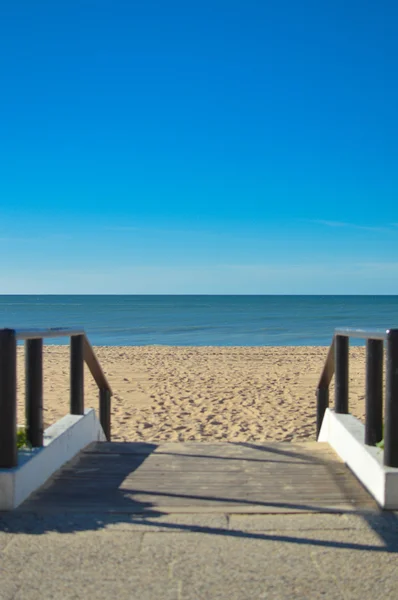 Sunny summer day with wooden walkway on sandy beach background — Stock Photo, Image