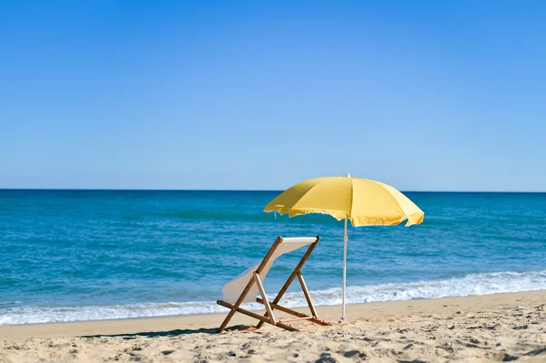 Vista trasera de la tumbona, tumbona bajo paraguas en la playa de arena . — Foto de Stock