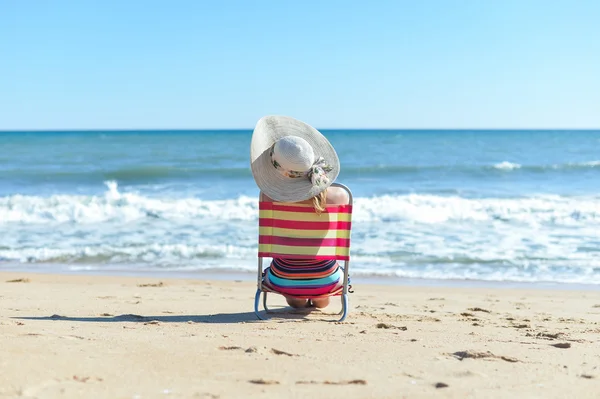 Vista trasera de la mujer en silla en la hora de verano sol luz playa vacaciones ubicación — Foto de Stock