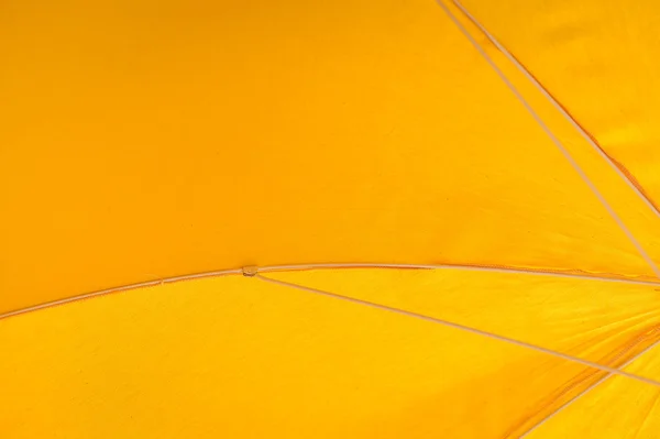 Closeup on yellow umbrella see-through blue sky and sun. Vacation holiday Royalty Free Stock Photos