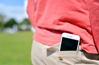 Smartphone--dan geri cep güneşli açık havada arka plan üzerine alarak Closeup adam