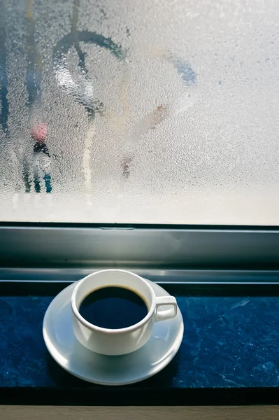 Kaffeetasse auf vernebeltem oder gefrorenem Hintergrundfenster — Stockfoto