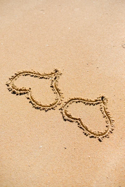 Dos corazones dibujados en la arena de una playa — Foto de Stock