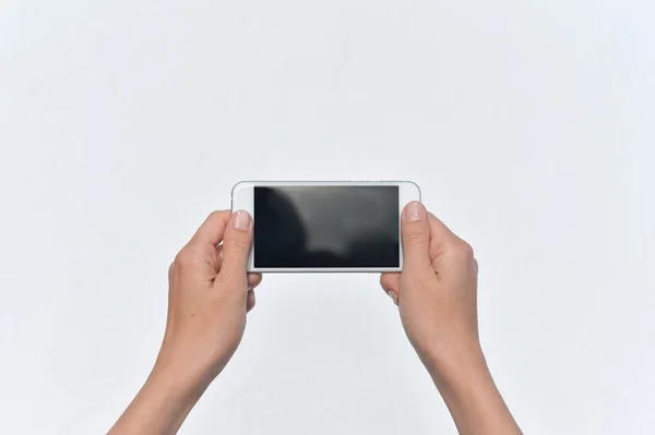 Ruce držící chytrý mobilní telefon na světlé zdi pozadí, detailní obrázek — Stock fotografie