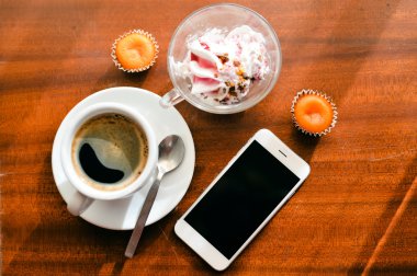 Ahşap arka plan üzerinde kahve fincanı, akıllı telefon, dondurma ve pasta Üstten Görünüm.