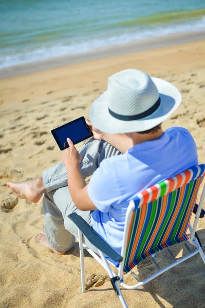 Działalności człowieka przy użyciu komputera typu tablet, tropikalnej plaży na zewnątrz. Widok z tyłu — Zdjęcie stockowe