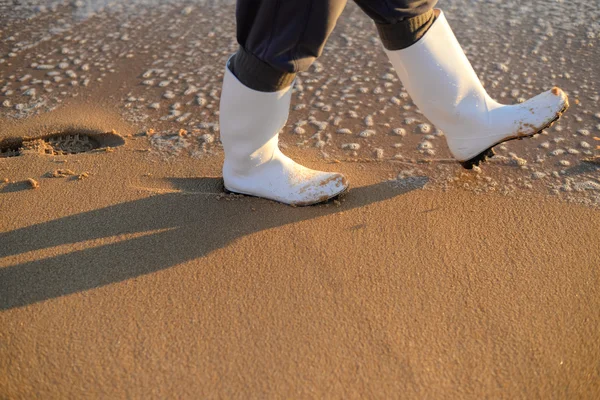 Person läuft in Gummistiefeln über Meeresstrand — Stockfoto
