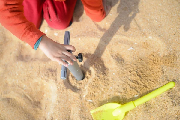 Criança com seus brinquedos brincando na praia . — Fotografia de Stock