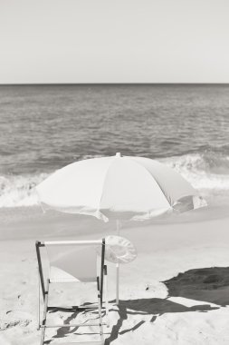 Kadın şapka, sandalye ve şemsiye tropikal plaj arka plan tatil çarpıcı üzerinde siyah beyaz fotoğraf