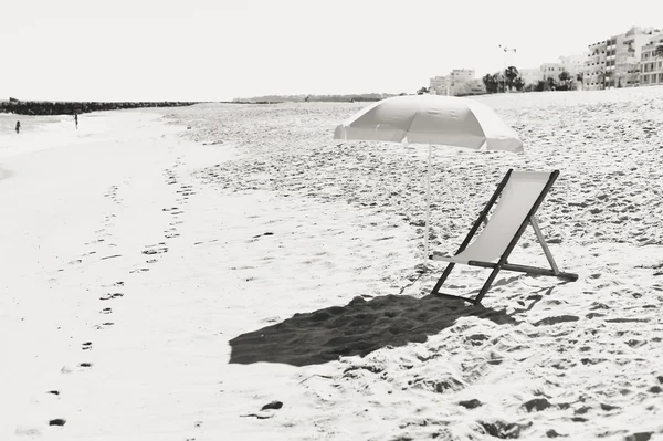 Μαύρο άσπρο φωτογραφία ομπρέλα και ξύλινη καρέκλα στην Ατλαντική αμμώδη παραλία — Φωτογραφία Αρχείου