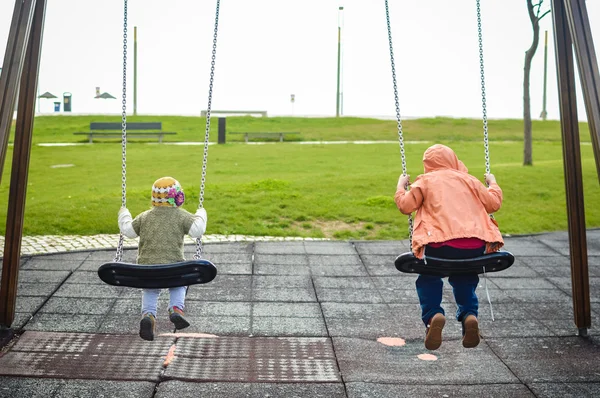 Visão traseira de crianças alegres felizes balançando no playground ao ar livre — Fotografia de Stock