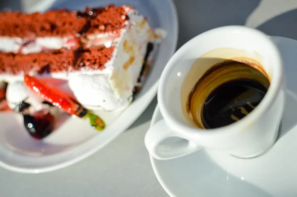 Soliga kopp kaffe och kaka i café på bord — Stockfoto