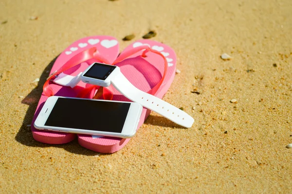 Primer plano del reloj inteligente y chanclas en el fondo de la playa. Estilo de vista superior, foto y video exterior — Foto de Stock