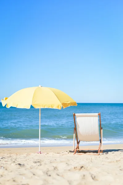 Vista trasera de la tumbona, tumbona bajo paraguas en la playa de arena . — Foto de Stock