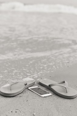 Siyah beyaz portre fotoğraf plaj arka plan üzerinde akıllı telefon.