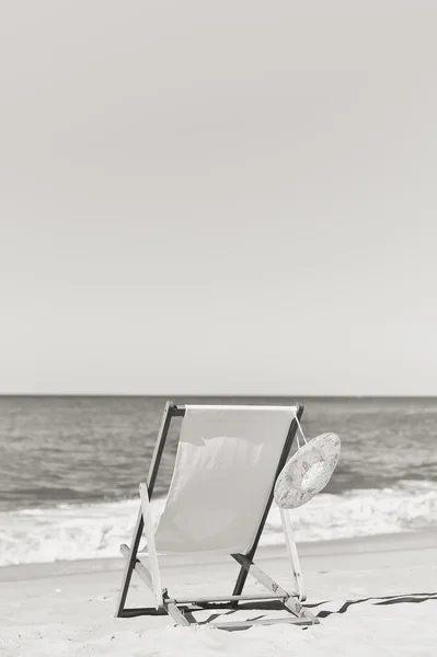 Fekete-fehér, a lenyűgöző, trópusi tengerparti nyaralás háttér nyugágy és női kalap. — Stock Fotó