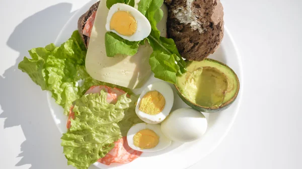 Avacado, pão, bacon e ovo com salada em prato na mesa, close up flat lay vista superior — Fotografia de Stock