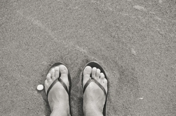 Svartvitt foto av beach utomhus bakgrund - fötter i flip flops. Idéer för semester — Stockfoto