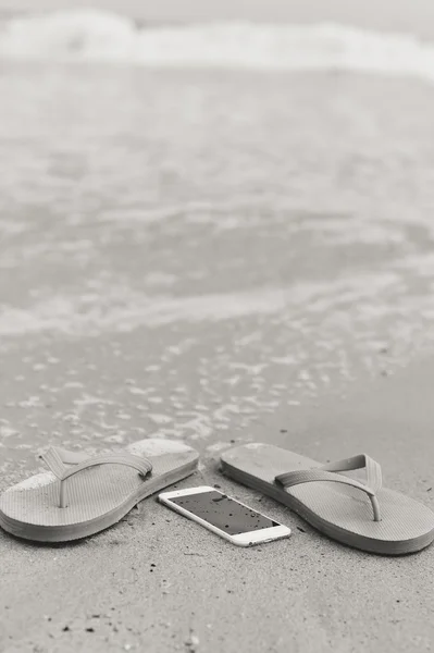 Foto de primer plano en blanco y negro del teléfono inteligente en el fondo de la playa . — Foto de Stock